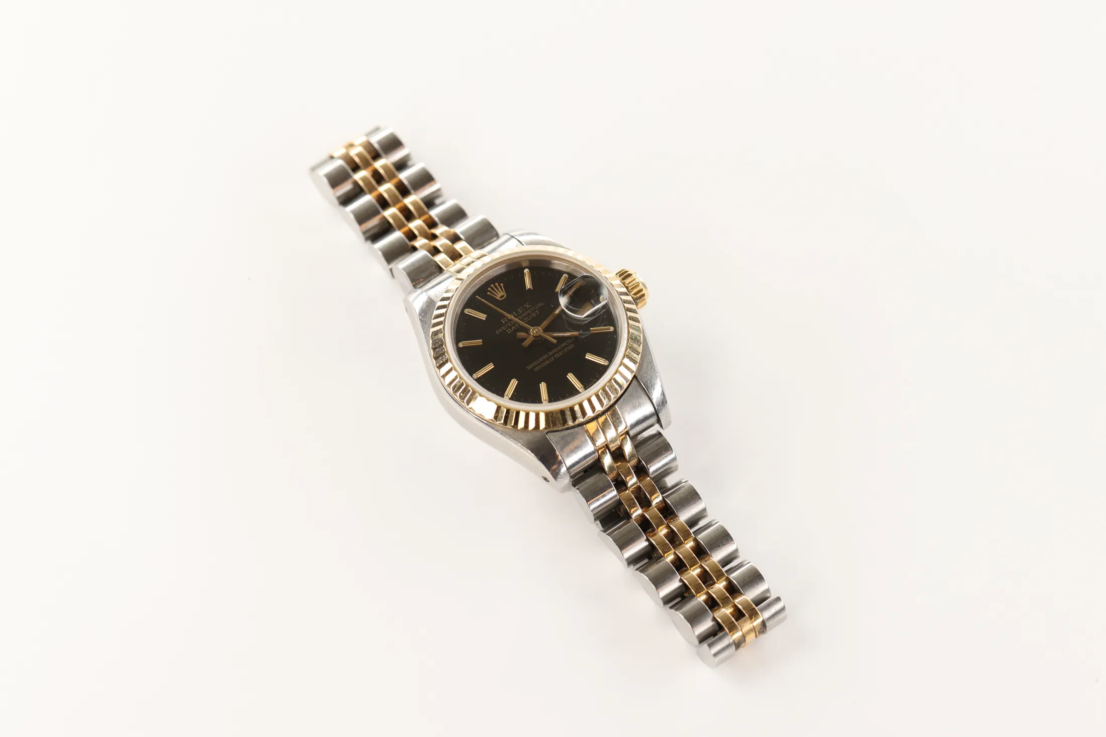 A two-tone gold and steel wristwatch with its bracelet resting on a white surface
