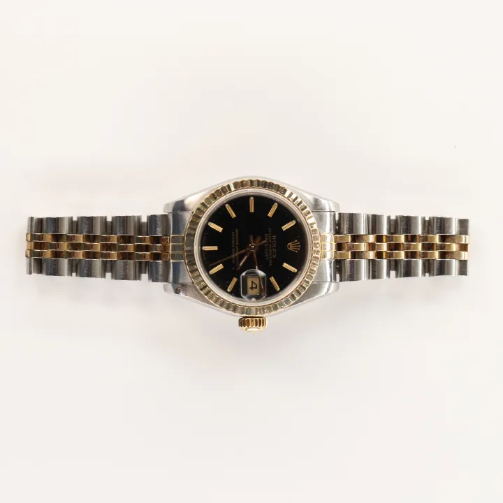 Two-tone stainless steel and gold Rolex Oyster Perpetual Datejust watch with a black dial, laid flat on a white background