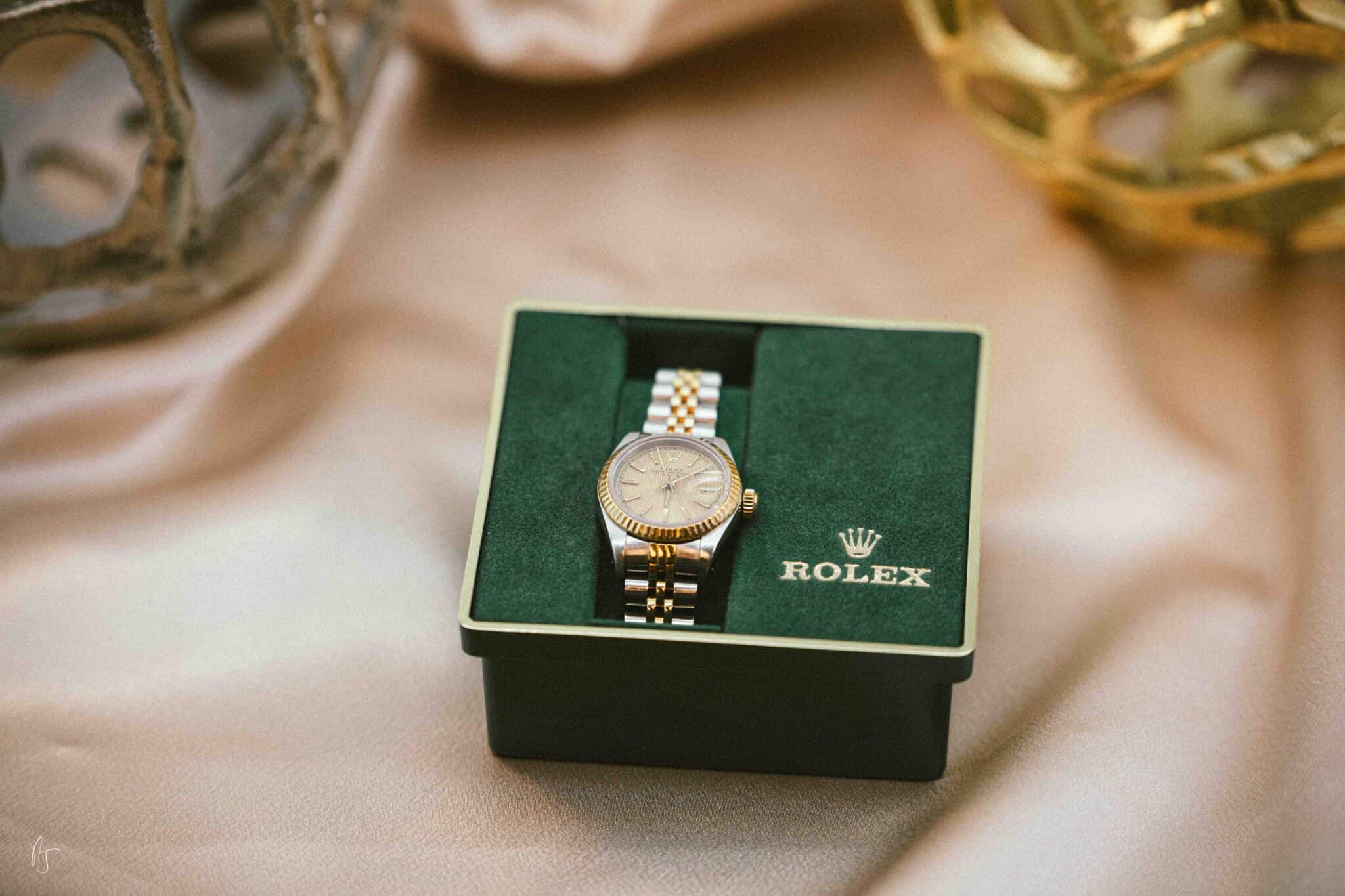 Rolex luxury watch in green box with gold accents.
