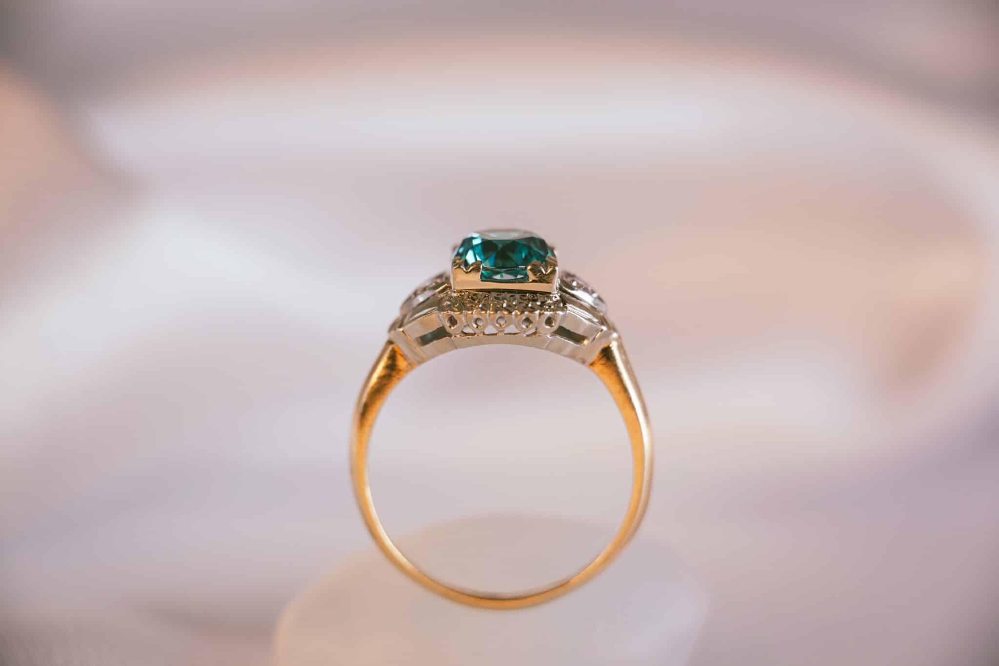 Engagement ring with emerald gemstone in gold setting.