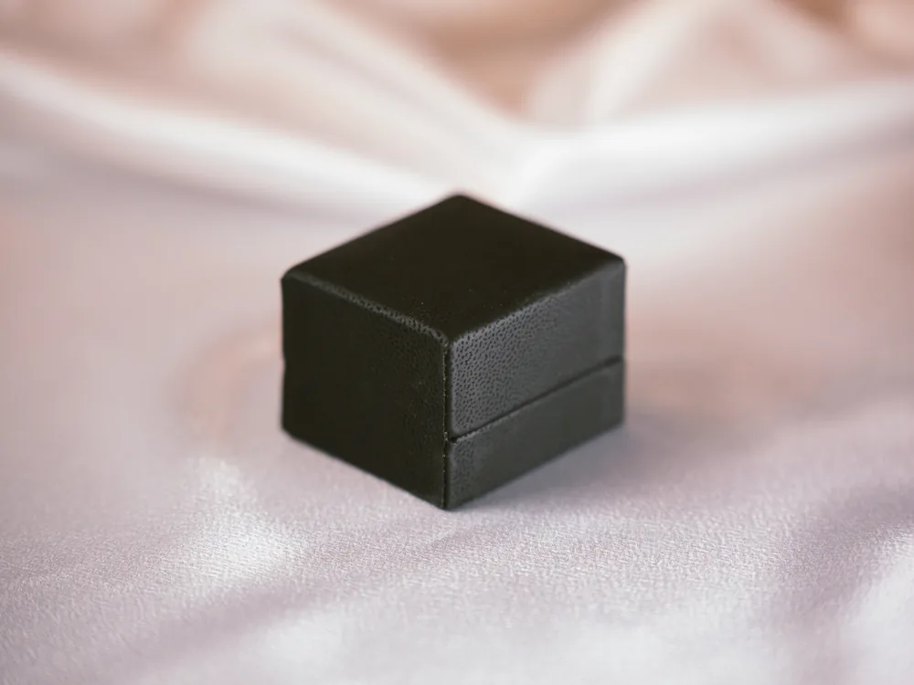 Black jewelry box resting on satin fabric
