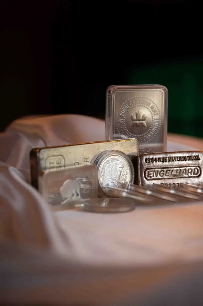 Silver bullion bars and a silver round on draped fabric