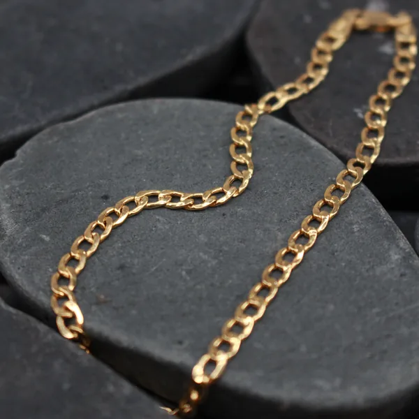 Gold curb link bracelet on dark stones
