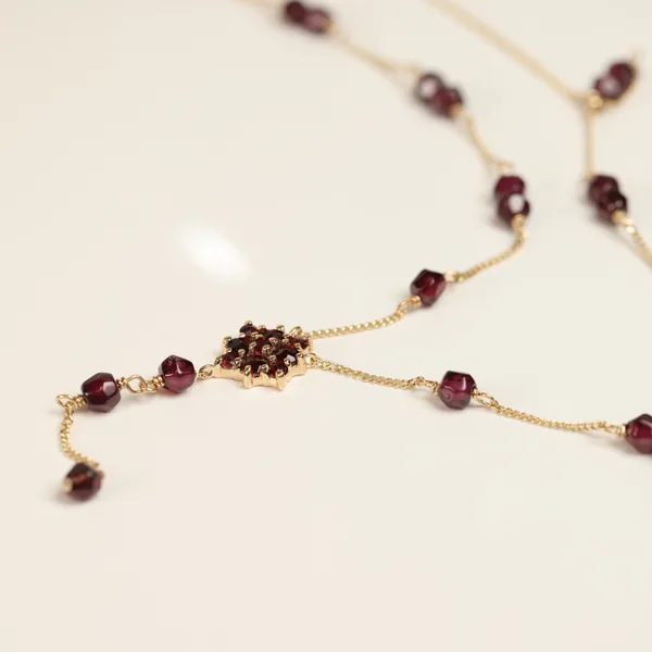Gold chain bracelet with small red gemstones