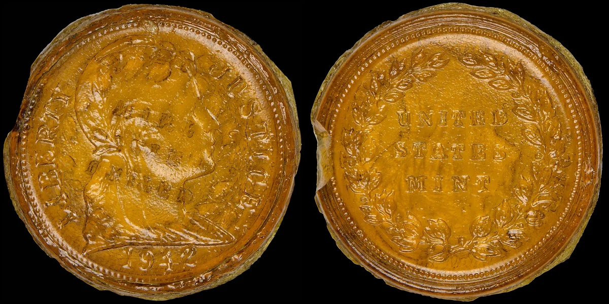 1942 Blue Ridge glass test cent in amber glass, front with a Liberty head and the 1942 date, back reading UNITED STATES MINT inside a wreath