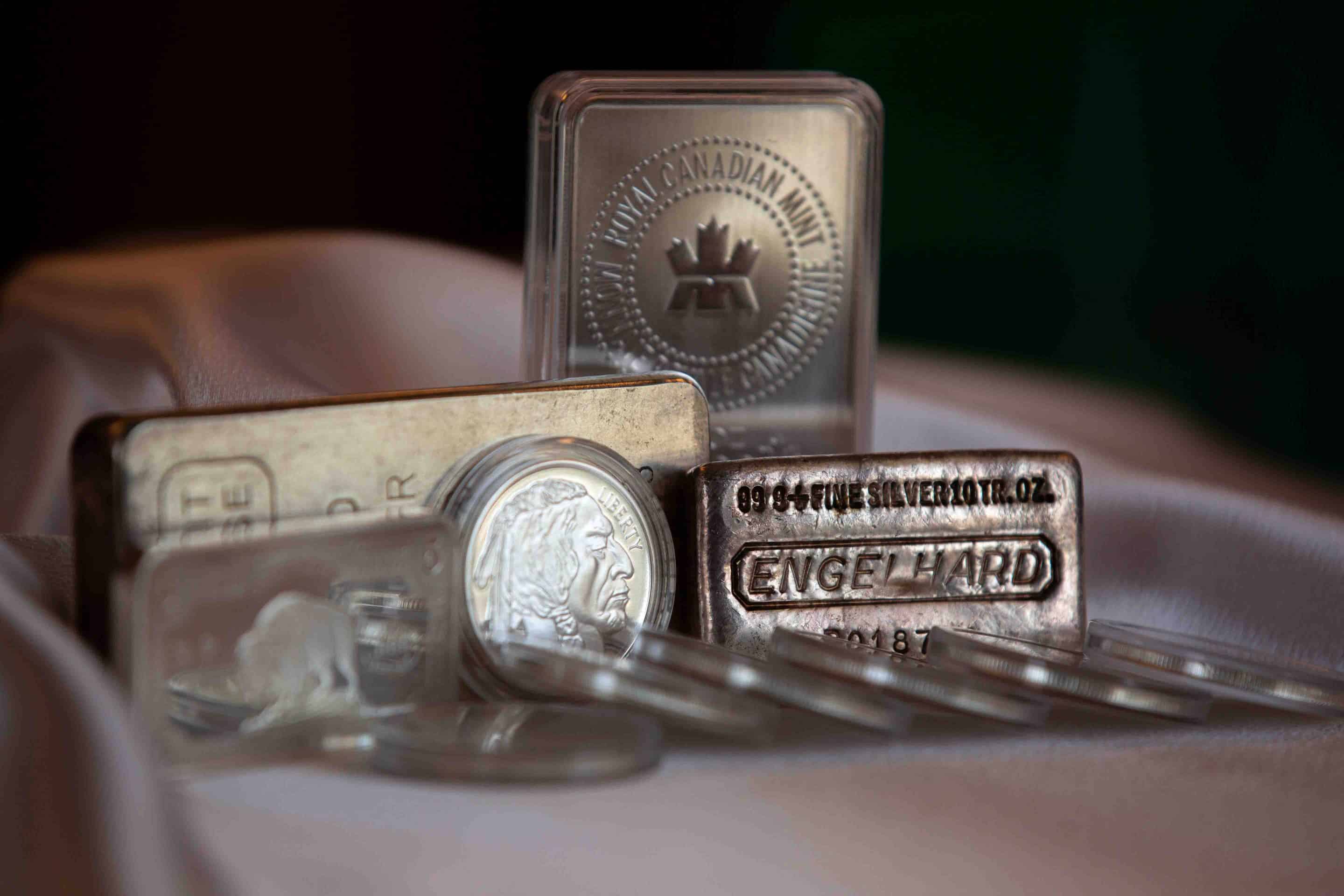 Silver bars and coins, gleaming with a metallic sheen, stacked up in a neat pile.