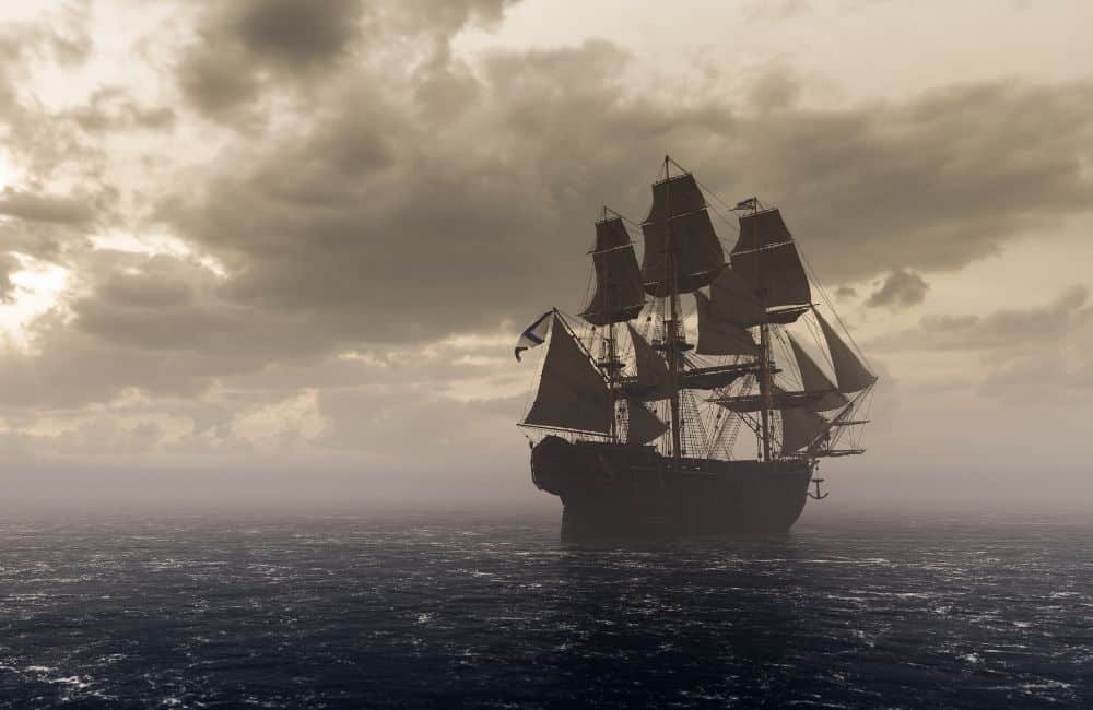A pirate ship is floating in the ocean under a cloudy sky.