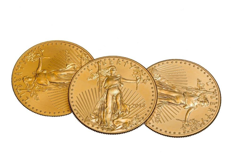 Three gold eagle coins on a white background.