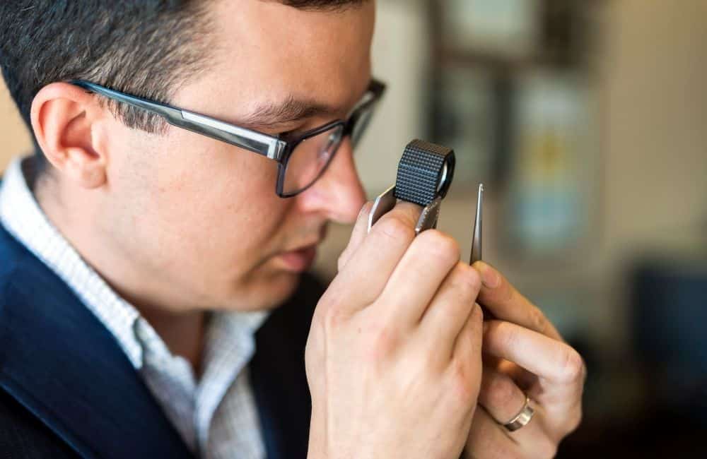 A man in glasses is looking at a watch.