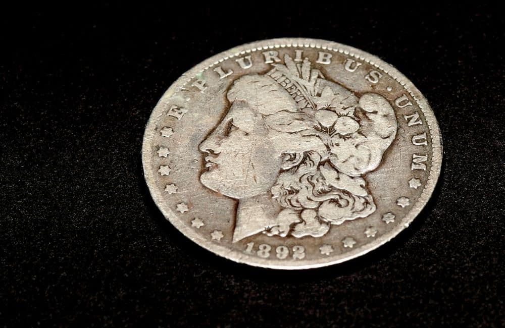 A silver morgan dollar on a black surface.