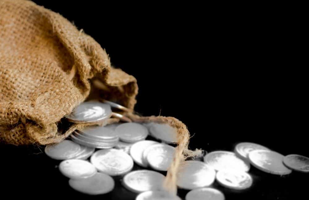 Silver coins in a sack on a black background.