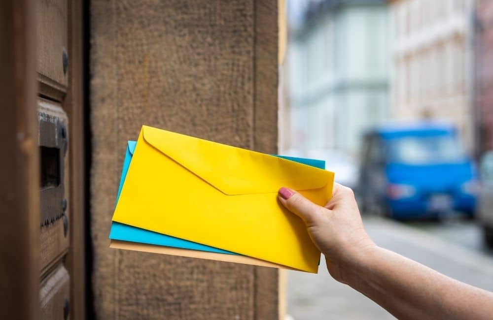 A hand is holding an envelope in front of a door.