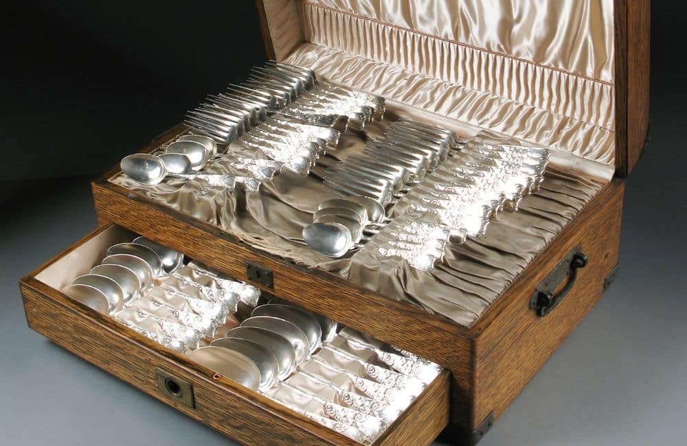 A wooden box filled with silver utensils.