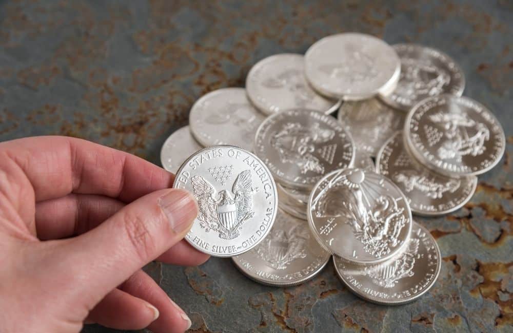 A hand holding a pile of silver coins.