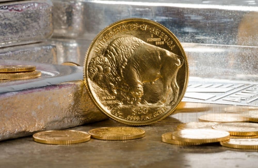 A gold bullion coin sits on top of a stack of gold coins.