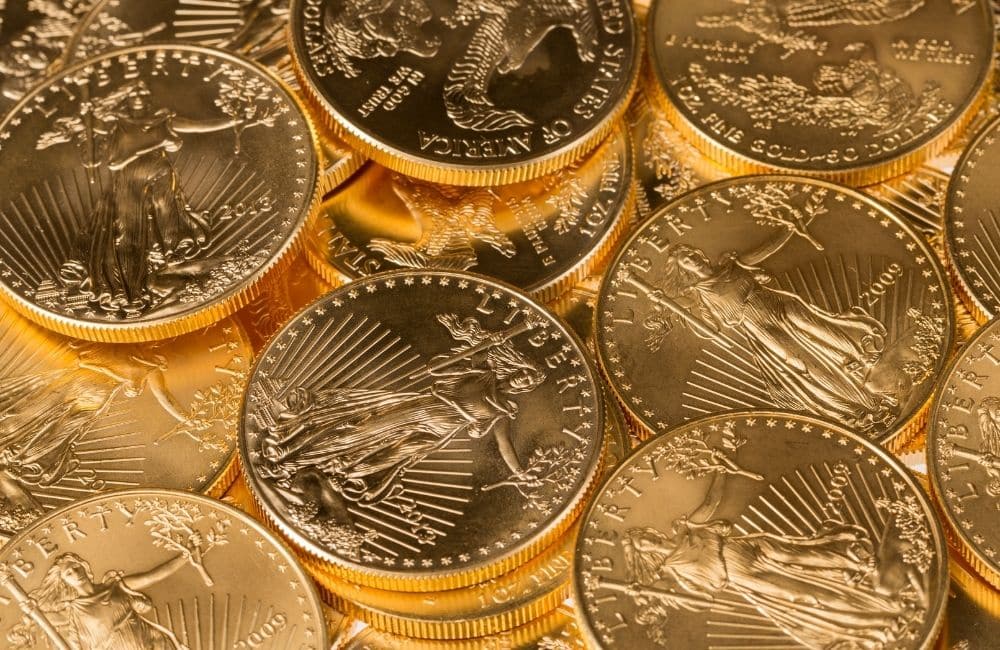 A pile of gold eagle coins on a white background.