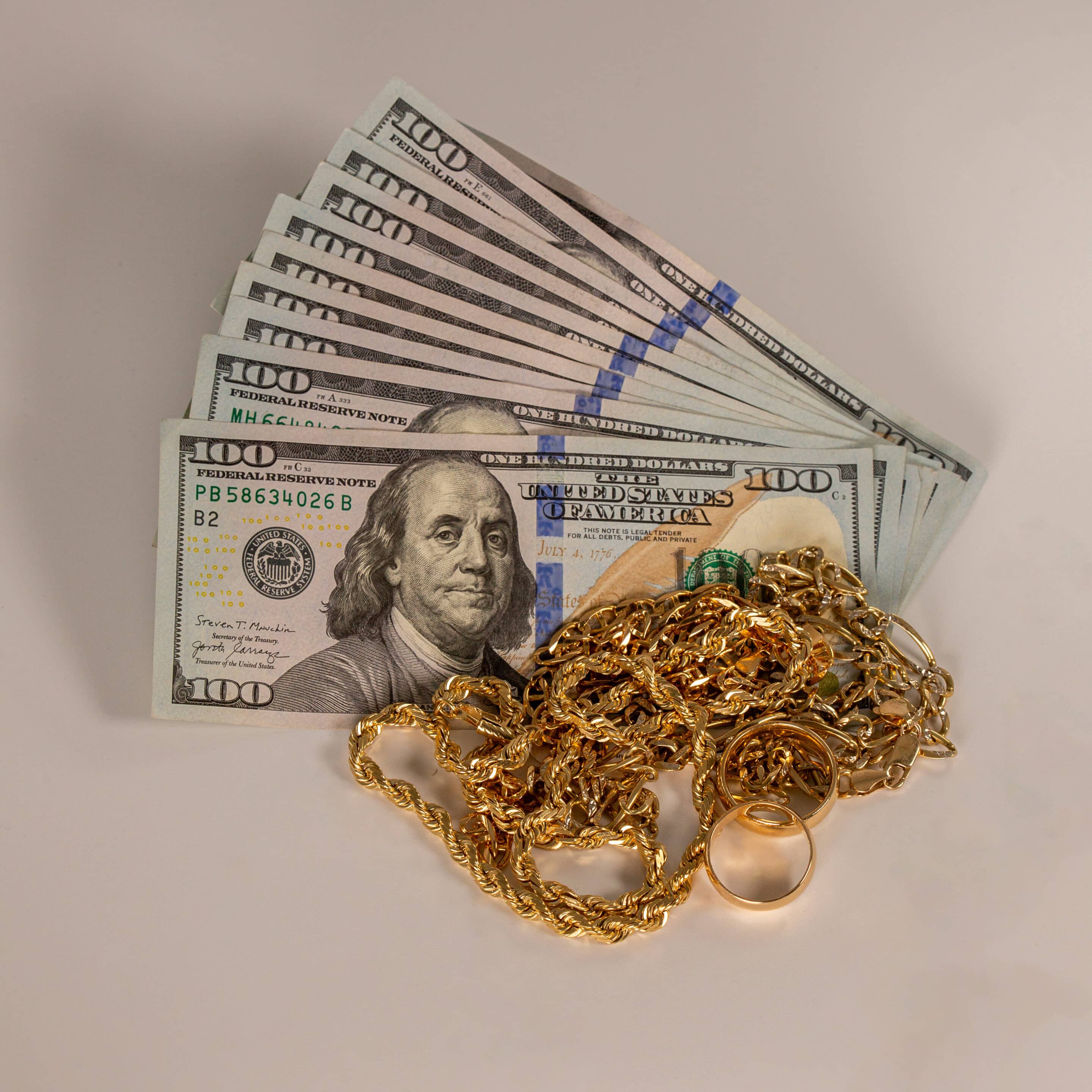 Scrap gold pieces placed on a pile of various currency bills.