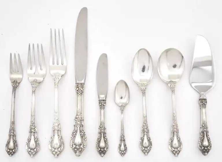 Silver cutlery set with ornate handles, including forks, knives, and spoons for luxury dining.