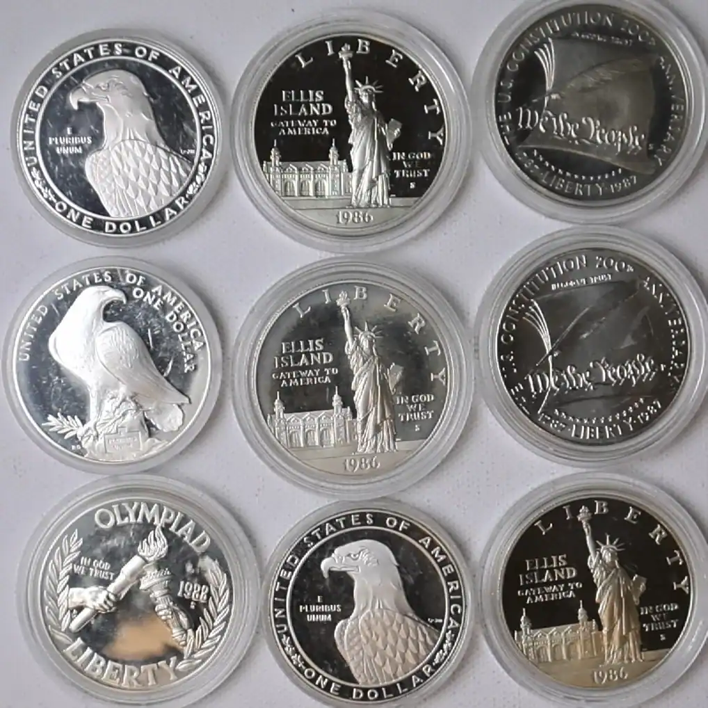 Collection of silver coins including American Eagle, Ellis Island, and Olympic commemoratives.